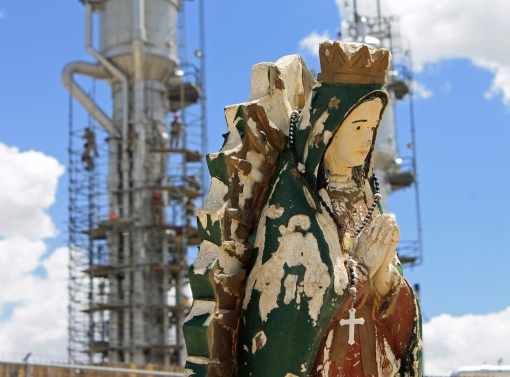 A natural gas processing plant outside of Bloomfield, New Mexico, has virtually swallowed up a Catholic cemetery. Virgen de Guadalupe with men working on distilling columns.